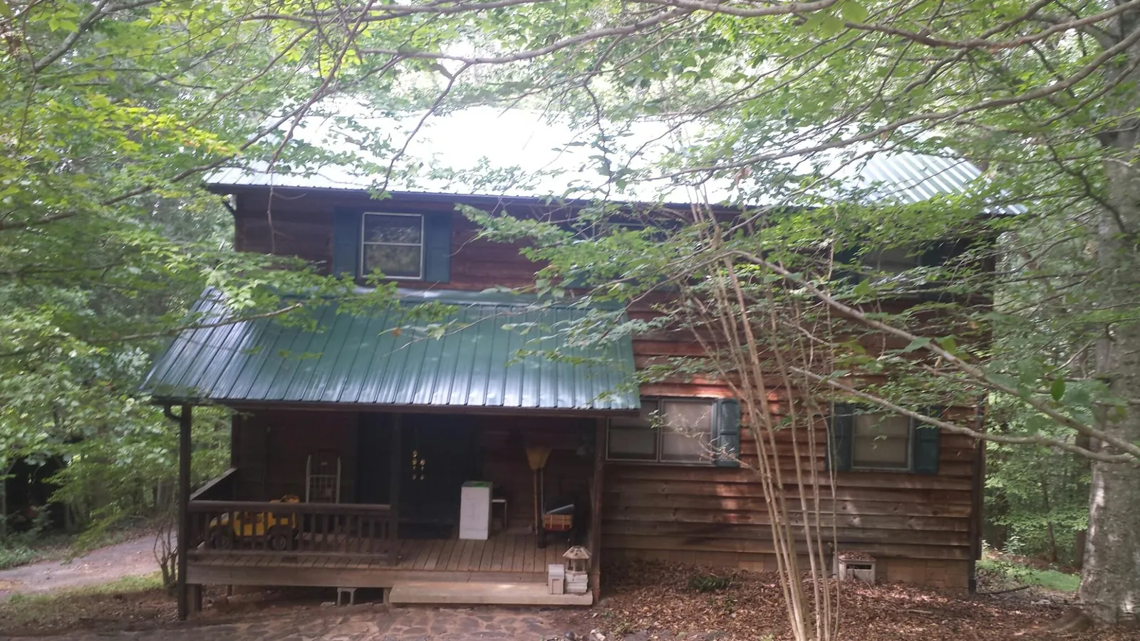 Green metal roof and covered porch on a log cabin in Ilion