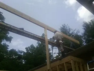 Carpenter setting a ridge beam over a new addition frame — Ice Dam Removal by Roofing Brothers in Ilion