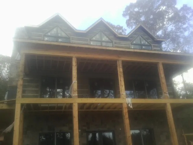Dormers and porch framing on a large log home under construction — Roof Coating work by our crew in Ilion