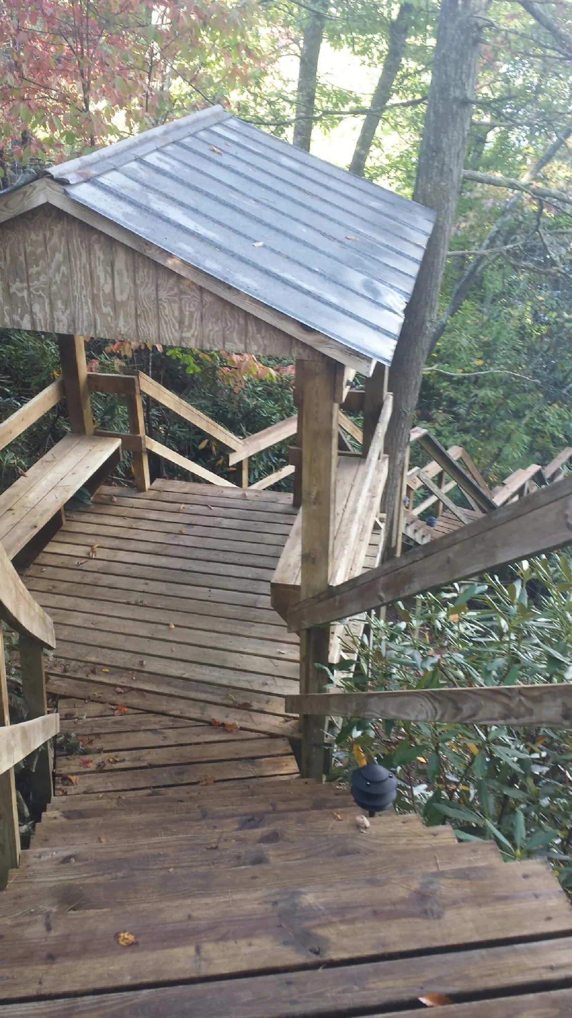 Metal roofed shelter over wooden steps on a wooded walkway — Skylight Repair & Installation work by our crew in Ilion