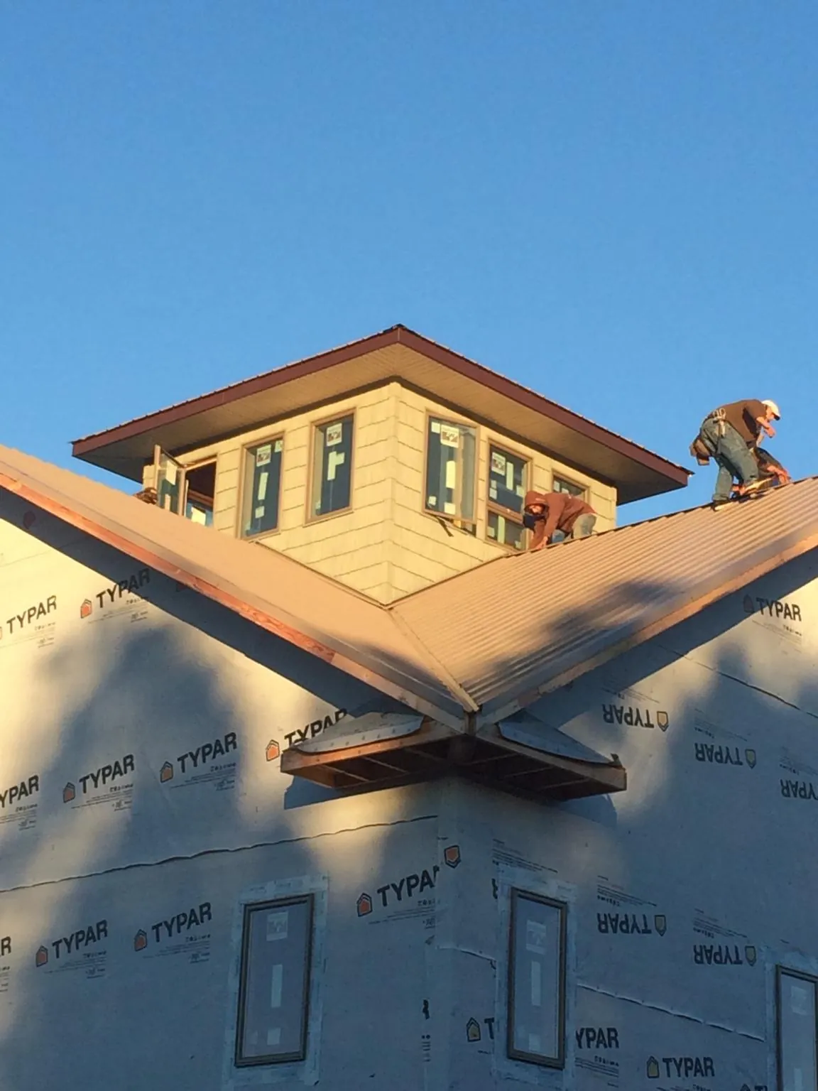 Roofers working around a rooftop cupola on a new metal roof at sunset — Roof Waterproofing in Ilion by Roofing Brothers